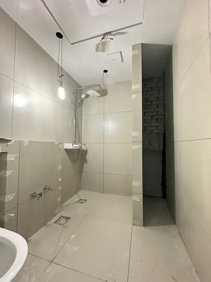 욕실 타일 접착제로 벽 타일을 붙이고 바닥 배수구를 맞춘 시공 중 욕실